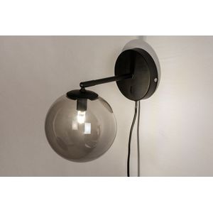 Zwarte wandlamp met bol van rookglas en schakelaar op de wandplaat