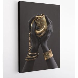 De handen van de zwarte vrouw met gouden juwelen. Oosterse armbanden op een zwart geschilderde hand. Gouden juwelen en luxetoebehoren op zwarte close-up als achtergrond. High Fashion art concept – Modern Art Canvas – Verticaal – 1274661100