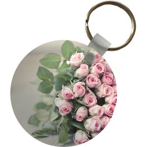 Sleutelhanger - Een grote boek van roze rozen ligt op een tafel. - Plastic - Rond - Uitdeelcadeautjes