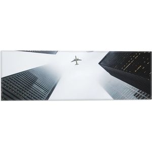 WallClassics - Vlag - Vliegtuig vliegend tussen Gebouwen - 60x20 cm Foto op Polyester Vlag