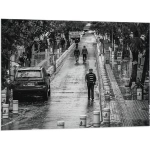WallClassics - Vlag - Man wandeldn door Dorpje (zwart/wit) - 100x75 cm Foto op Polyester Vlag