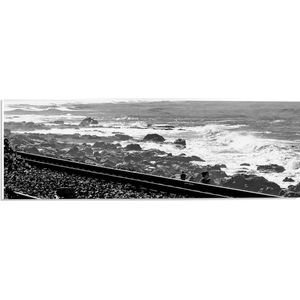 WallClassics - PVC Schuimplaat- Treinrails aan het Zeewater (zwart/ wit) - 60x20 cm Foto op PVC Schuimplaat