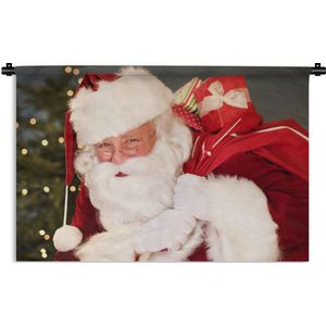 Wandkleed Kerst - Een portret van de Kerstman die een rode zak over zijn schouder draagt Wandkleed katoen 180x120 cm - Wandtapijt met foto XXL / Groot formaat!