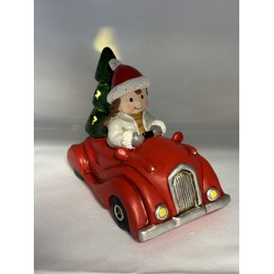 Kerstbeeldje meisje in rode auto met LED - grijs vest + groene kerstboom - polyresin - 12 cm hoog x 16 cm x 8 cm – Kerstdecoratie