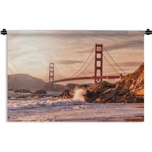 Wandkleed Golden Gate Bridge - Golden Gate Bridge met wilde golven die op de rotsen klappen in San Francisco Wandkleed katoen 150x100 cm - Wandtapijt met foto