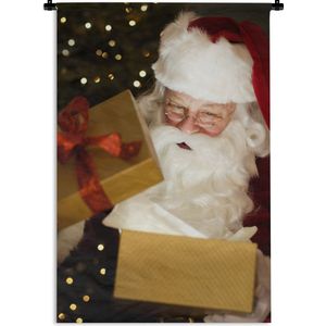 Wandkleed Kerst - Een portret van de kerstman terwijl hij kerstcadeautjes opent Wandkleed katoen 60x90 cm - Wandtapijt met foto