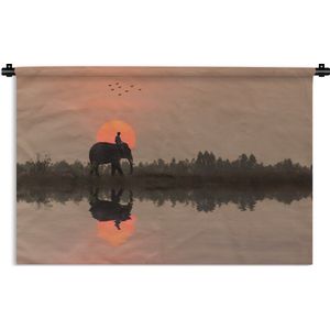 Wandkleed Rijstvelden - Een olifant bij een rijstveld in Thailand tijdens een zonsondergang Wandkleed katoen 90x60 cm - Wandtapijt met foto