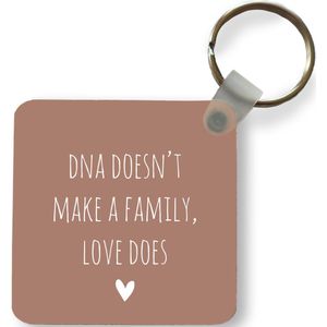 Sleutelhanger - Uitdeelcadeautjes - Engelse quote DNA doesn't make a family, love does met een hartje tegen een bruine achtergrond - Plastic