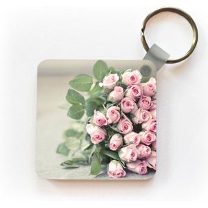 Sleutelhanger - Uitdeelcadeautjes - Een grote boek van roze rozen ligt op een tafel. - Plastic