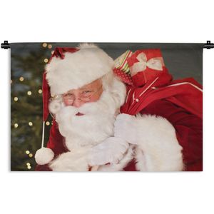 Wandkleed Kerst - Een portret van de Kerstman die een rode zak over zijn schouder draagt Wandkleed katoen 150x100 cm - Wandtapijt met foto