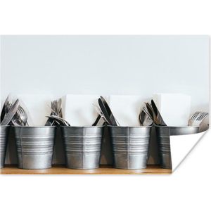 Metalen emmers met verschillende soorten bestek en servetten die op een houten plank tegen een witte muur staan 60x40 cm