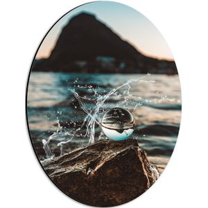 Dibond Ovaal - Glazen Bol op een Rots langs het Water - 30x40 cm Foto op Ovaal (Met Ophangsysteem)