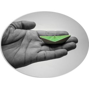 PVC Schuimplaat Ovaal - Miniatuur Groene Origami Boot op Zwart- witte Hand - 68x51 cm Foto op Ovaal (Met Ophangsysteem)
