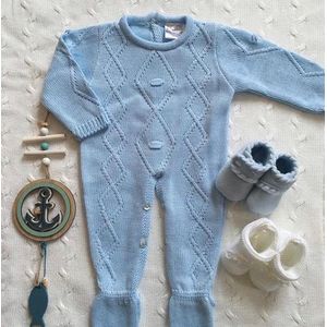 Lichtblauw gebreide onesie met ingewevenpatroon. Knoopsluiting aan achterzijde en tussen de beentjes.
