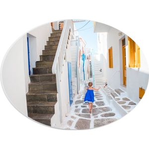 PVC Schuimplaat Ovaal - Meisje in Blauwe Jurk door de Straten van Santorini, Griekenland - 40x30 cm Foto op Ovaal (Met Ophangsysteem)