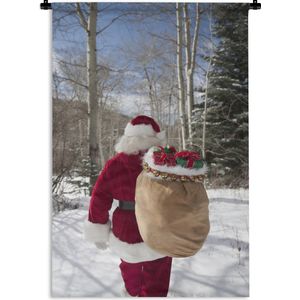 Wandkleed Kerst - De kerstman loopt met een zak vol met kerstcadeaus door een bos Wandkleed katoen 120x180 cm - Wandtapijt met foto XXL / Groot formaat!