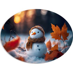 PVC Schuimplaat Ovaal - Sneeuwpop met Bruine Sjaal en Muts in de Sneeuw tussen de Herfstbladeren - 80x60 cm Foto op Ovaal (Met Ophangsysteem)