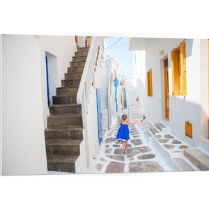 PVC Schuimplaat - Meisje in Blauwe Jurk door de Straten van Santorini, Griekenland - 105x70 cm Foto op PVC Schuimplaat (Met Ophangsysteem)