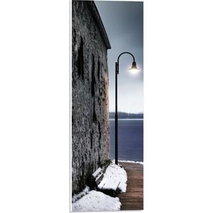 PVC Schuimplaat - Lantaarnpaal op Pad langs Stenen Muur aan de Zee - 20x60 cm Foto op PVC Schuimplaat (Met Ophangsysteem)