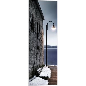 PVC Schuimplaat- Lantaarnpaal op Pad langs Stenen Muur aan de Zee - 30x90 cm Foto op PVC Schuimplaat