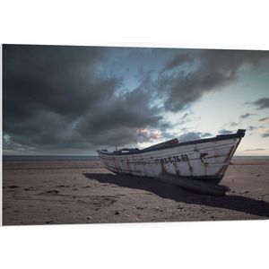 WallClassics - PVC Schuimplaat - Witte Boot op het Strand onder Donkere Wolken - 105x70 cm Foto op PVC Schuimplaat (Met Ophangsysteem)