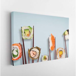Traditionele japanse sushi-stukken geplaatst tussen eetstokjes, gescheiden op lichtblauwe pastelachtergrond. Zeer hoge resolutie afbeelding. - Moderne kunst canvas - Horizontaal - 1090150760 - 115*75 Horizontal